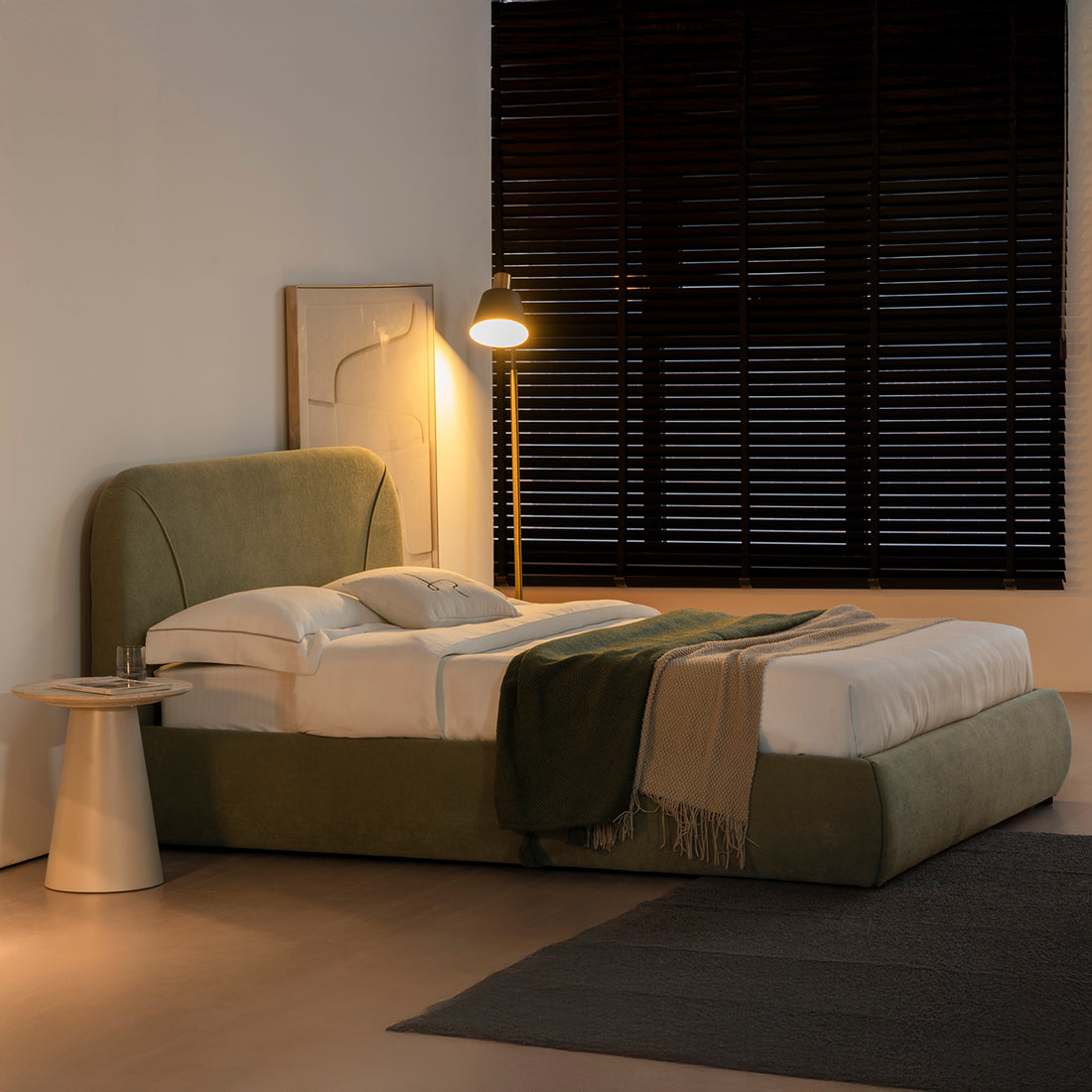 foto lifestyle de la cama matrimonial Vigo de noche en una habitación, junto a una lampara de piso, un cuadro y una mesa lateral