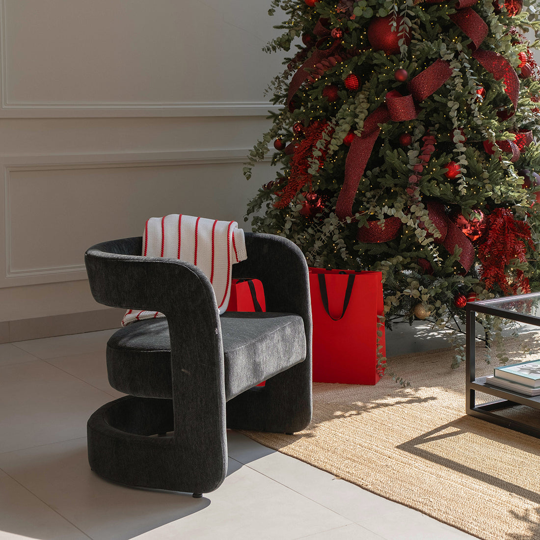SILLÓN KHATT EN SALA CON ARBOL DE NAVIDAD Y BOLSAS ROJAS DE REGALO