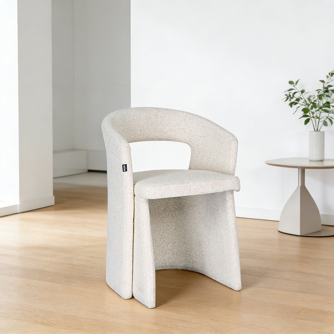 Silla Pavia beige vista en perspectiva dentro de un cuarto con mesa lateral a un lado sobre piso de madera