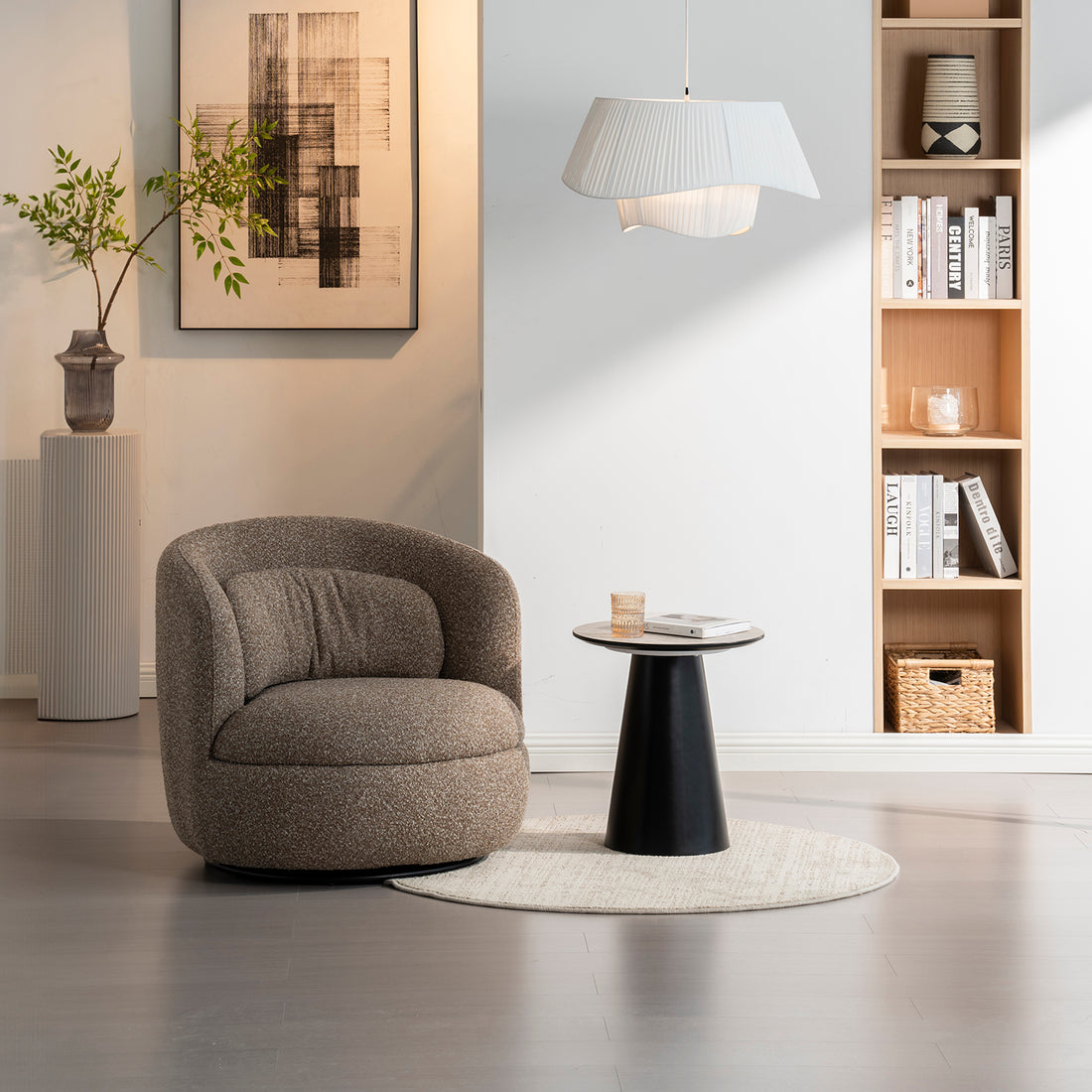 Sillón Victoria con mesa lateral color negro, con un vaso de agua y un libro. Debajo de un cuadro artístico, con pared blanca y una mesa lateral con un florero
